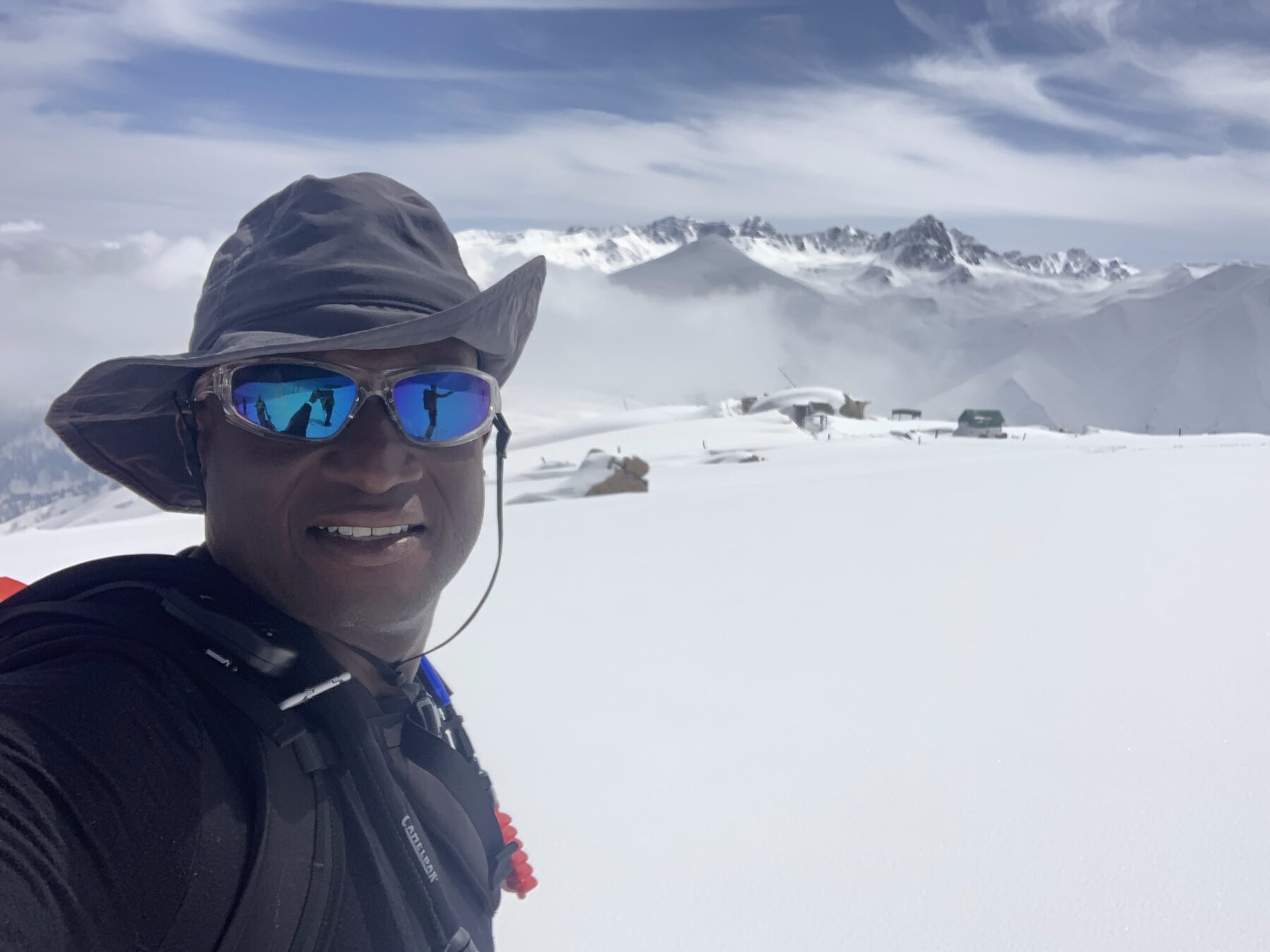 Bennett Wyche at a snowy mountain summit, peaks behind him