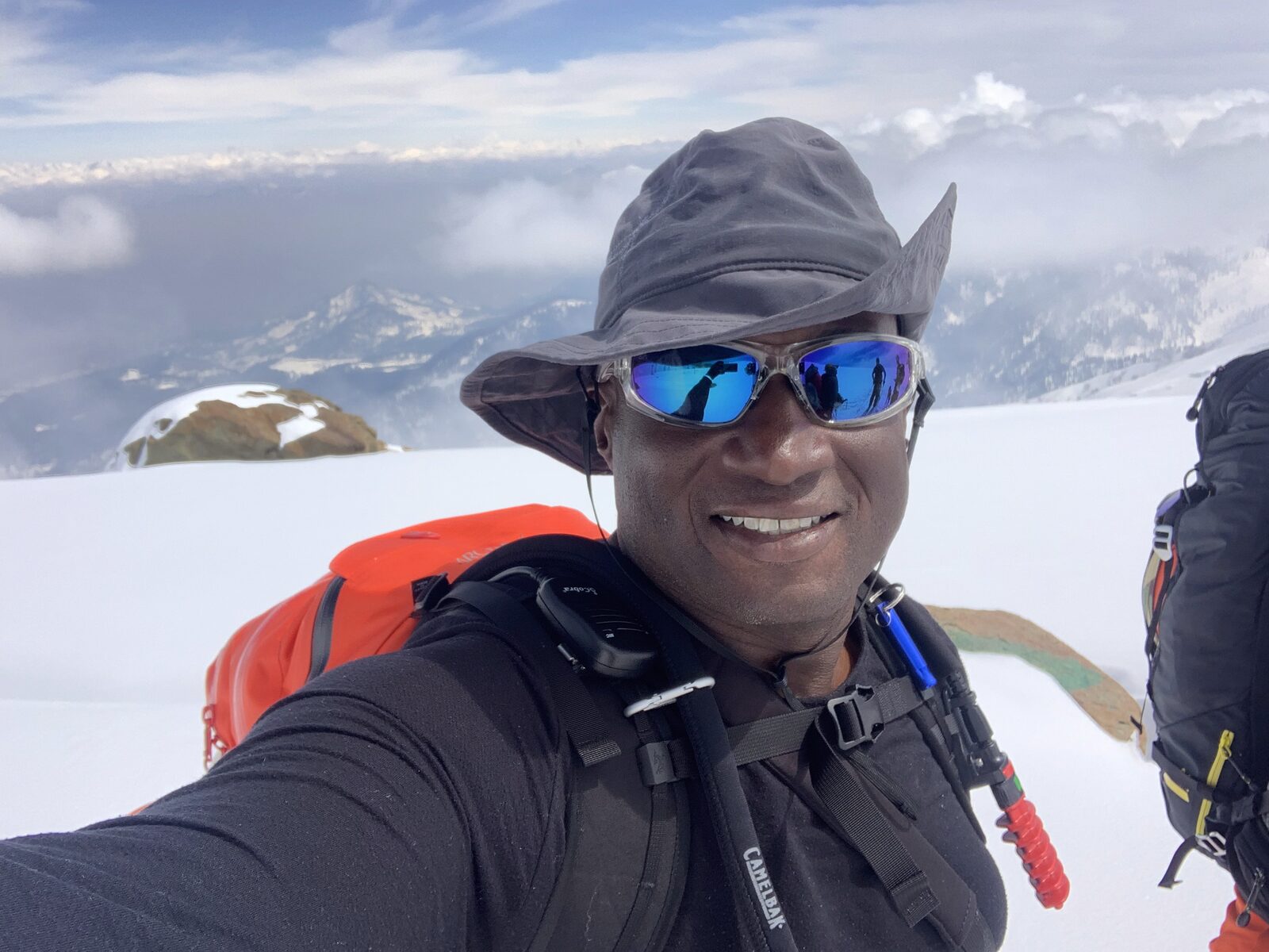 Bennett Wyche on a snowy ridge, clouds and peaks below